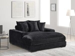 Black corduroy chaise lounge with pillows.